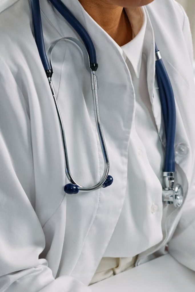 Close-up of a healthcare professionals stethoscope draped around a white coat, symbolizing clinical care.